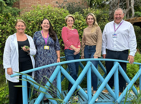 Eikon team standing on the bridge in the garden with Surrey's Police and Crime Commissioner